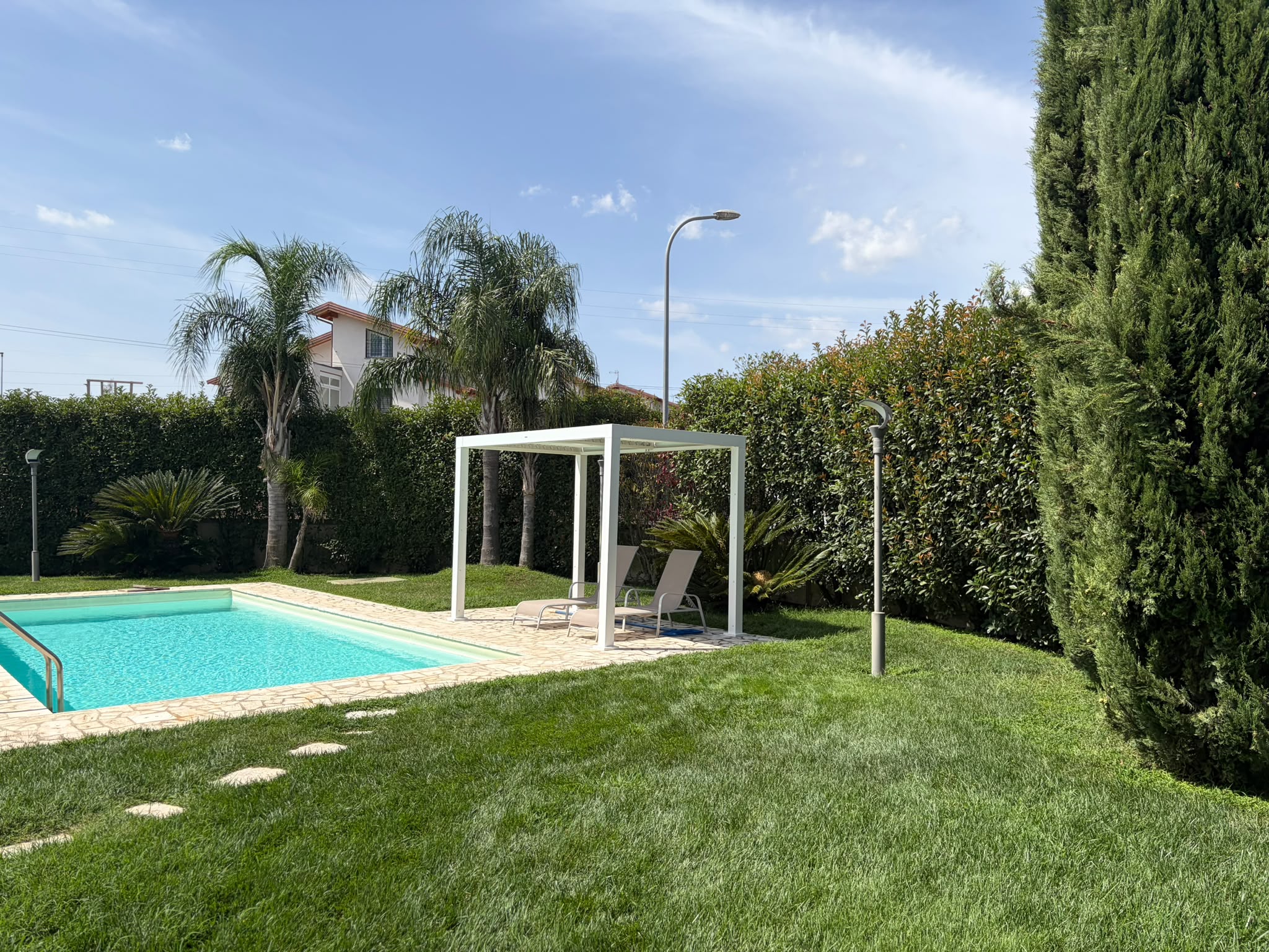 Area relax e pergola bordo piscina con prato curato